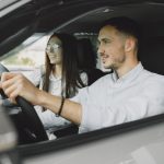 A young couple smiling while driving together in a modern car interior.
